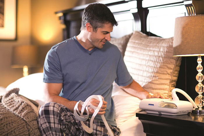 CPAP マシンを使用しているベッドに座っている男性